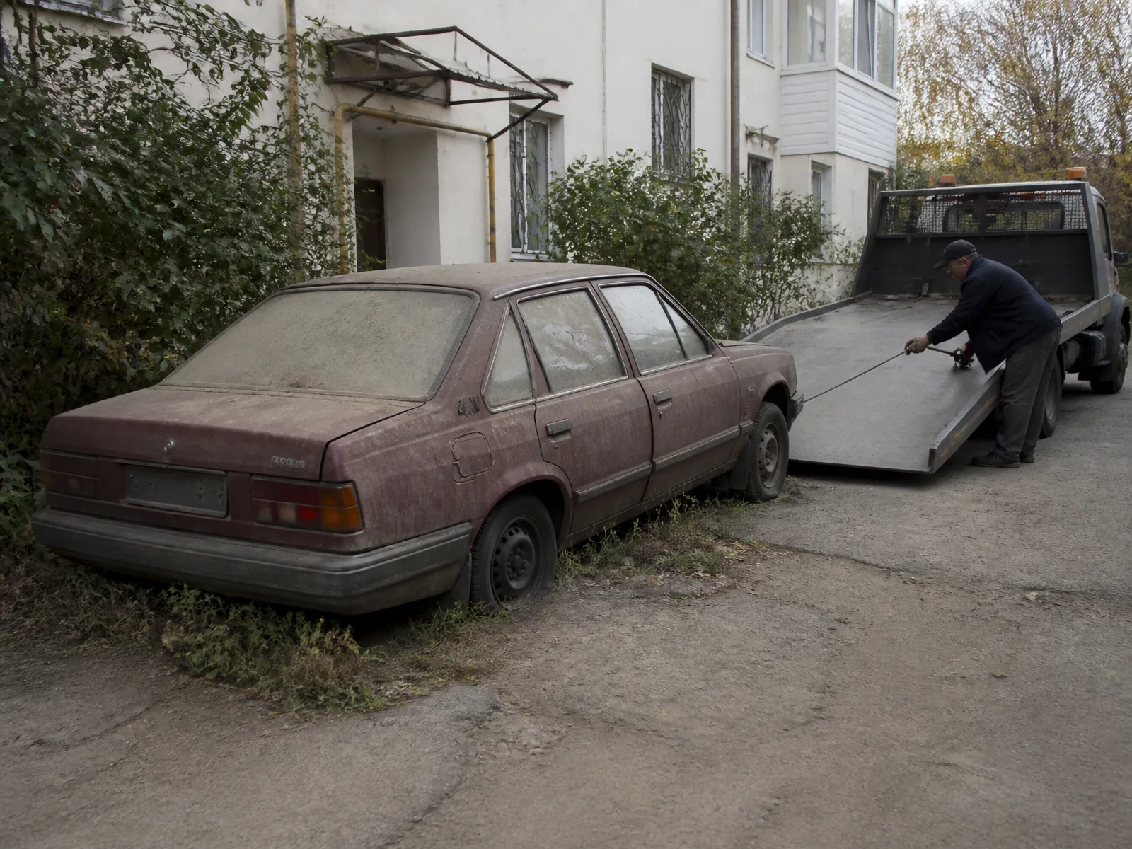 Dlhodobo odstavené auto sa navijakom ťahá na plošinu odťahovky